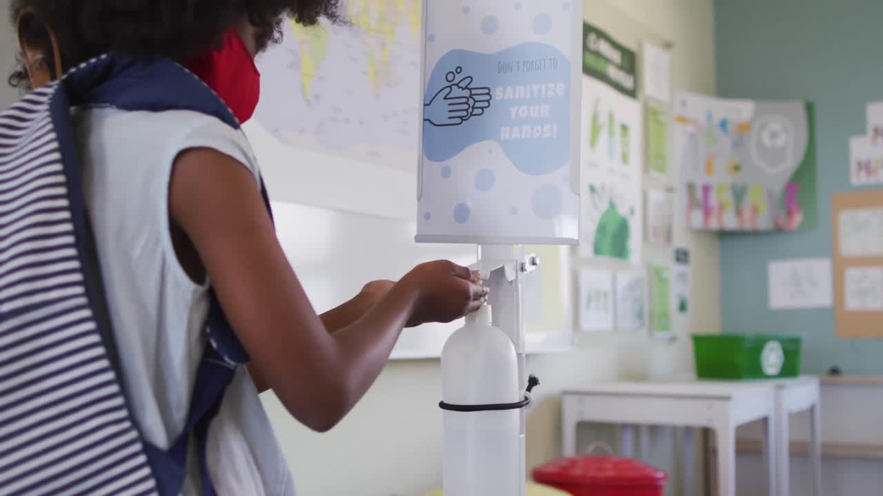 Menina usando máscara facial higienizando as mãos na escola