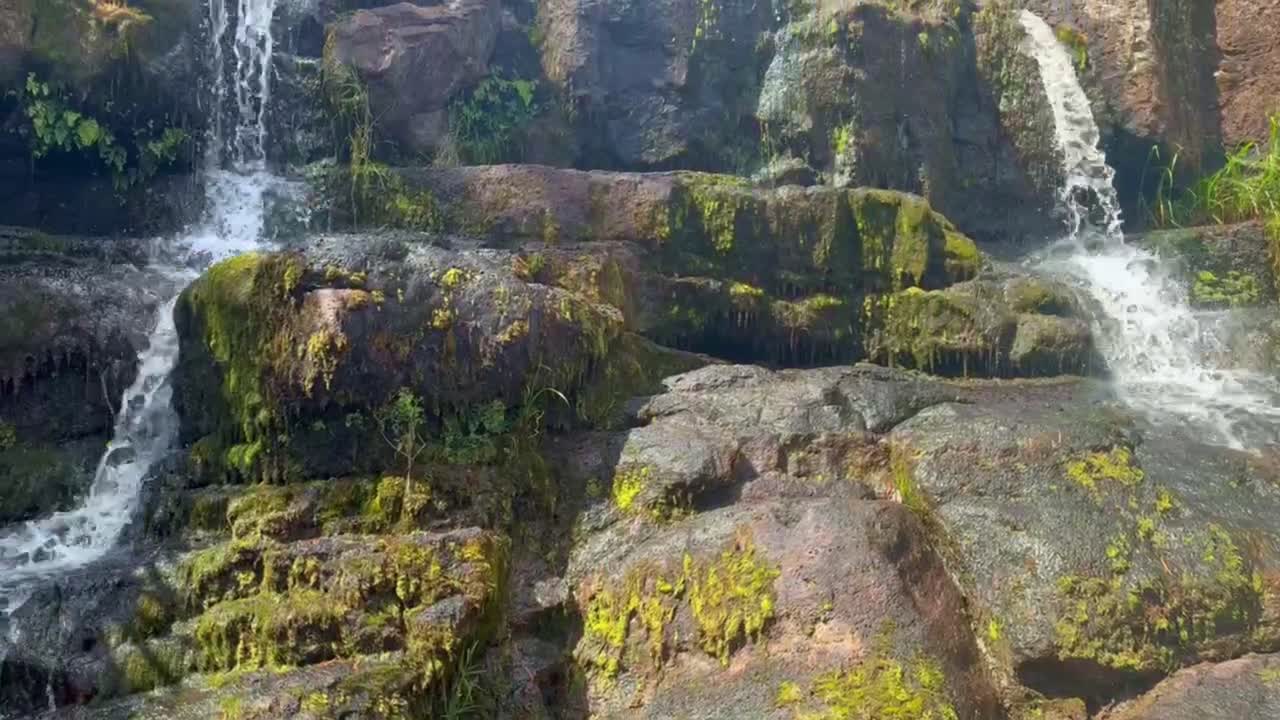 Cinematic close-up booming up shot of a small waterfall along the Waimea Canyon Lookout Trail in Kaua'i, Hawai'i