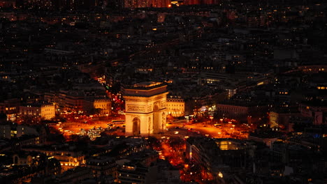 aerial of the illuminated arc de triomphe in the city of paris, france at night