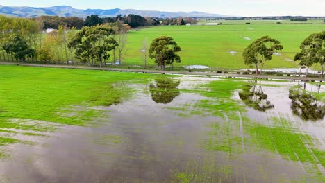 aerial view of flooded fields in christchurch, highlighting waterlogged terrain and surrounding greenery under clear skies
