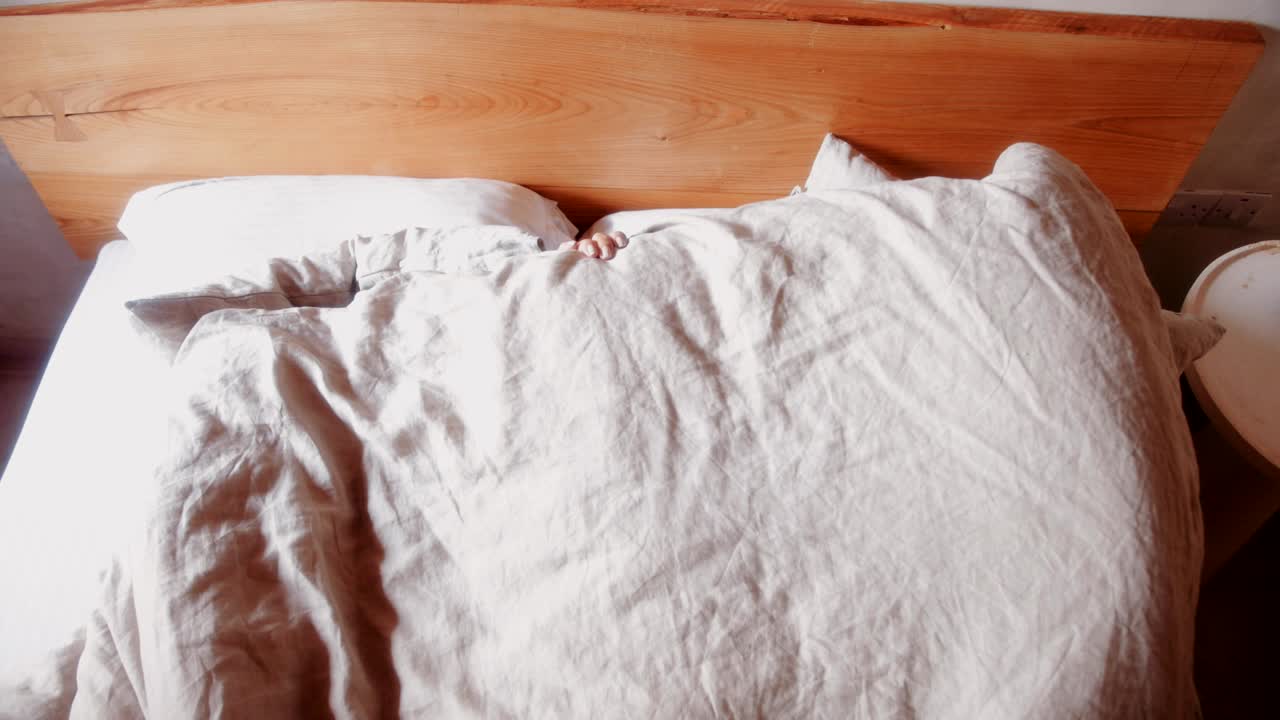 행복한 어머니와 아들이 침대에서 피카부 놀고 있습니다.