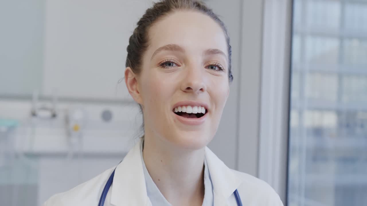 Portrait of happy caucasian female doctor laughing in hospital, in slow motion