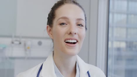 portrait of happy caucasian female doctor laughing in hospital, in slow motion