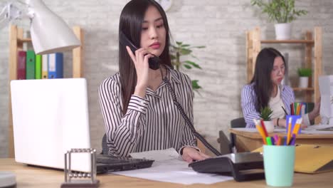 young asian manager answers phone calls in the workplace