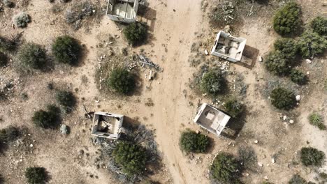 ruinas de edificios abandonados estructuras de hormigón destruidas por la violencia de las bandas del cártel en el alto desierto del sur de california en un día nublado con un estado de ánimo apocalíptico aérea de arriba hacia abajo dolly 60fps