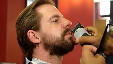 barber trimming mans mustache with trimmer 4k