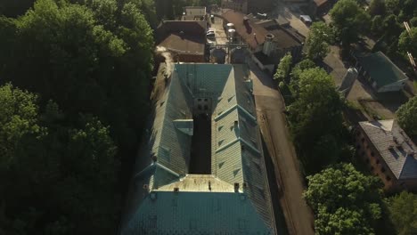 a historic, vintage brewery with smoking chimneys, surrounded by green trees during summer in poland's silesia region
