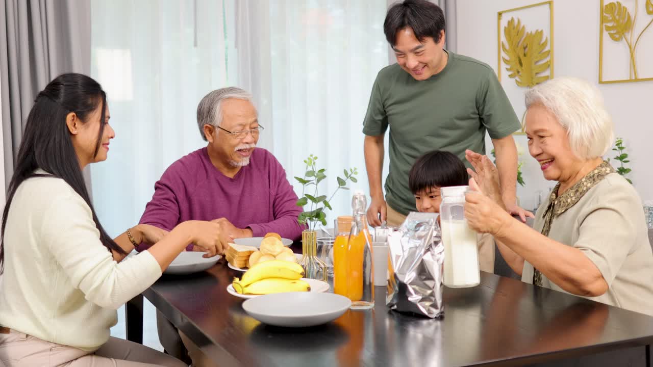 Four family members share breakfast, smiling and interacting warmly in a bright, cozy dining room