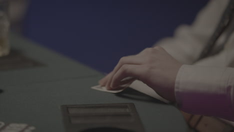 person with a white costume taking poker cards from the table and checking them out in slowmotion log