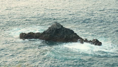 Toma-Cinematográfica-En-Cámara-Lenta-De-Roca-Volcánica-En-Alta-Mar-En-Tenerife,-Olas-Espumosas.