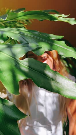 woman hiding behind tropical leaves