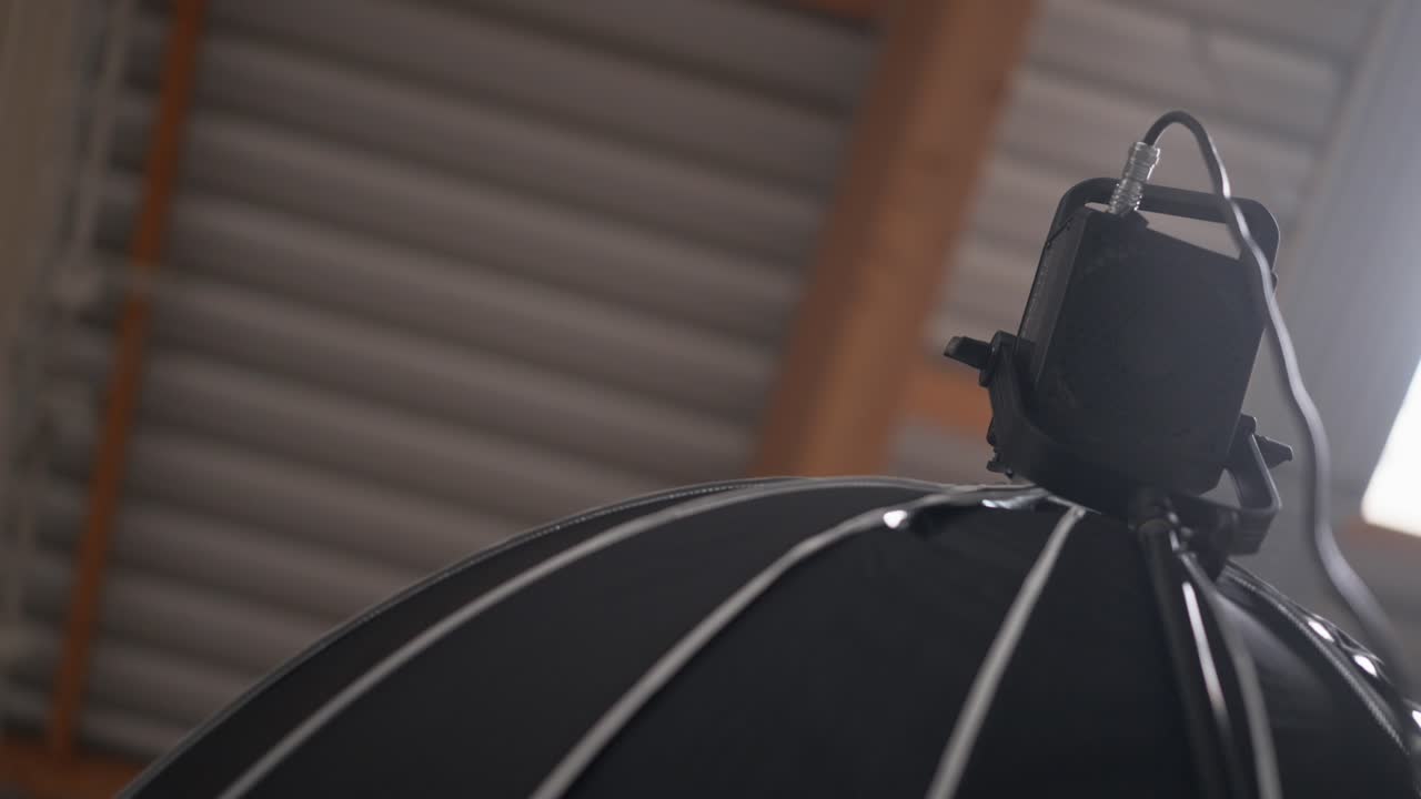 LED video light with big soft box mounted high up on tripod, low angle