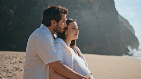 pareja embarazada mirando el paisaje del mar de pie playa de arena vacaciones de verano primer plano