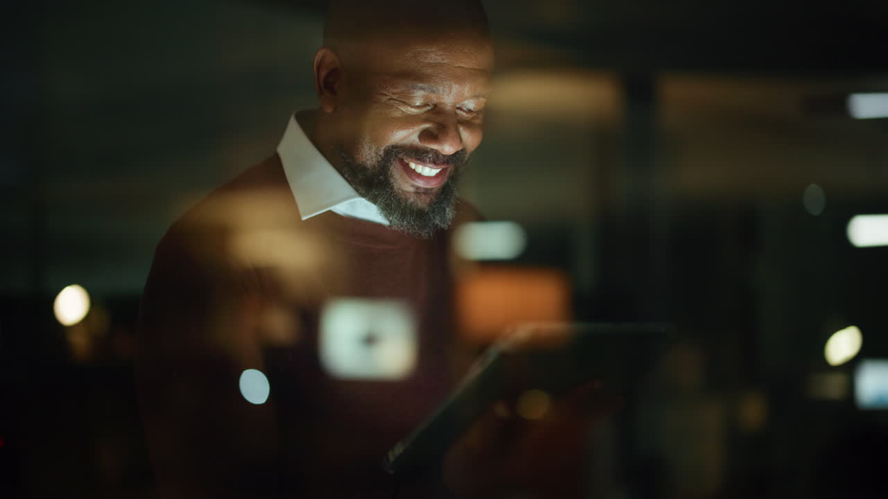 Man smiles using technology in his office at night