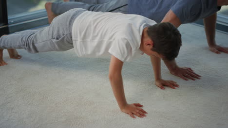 Padre-E-Hijo-Entrenando-Juntos-En-Casa.-Papá-Y-Niño-Haciendo-Flexiones-En-El-Interior