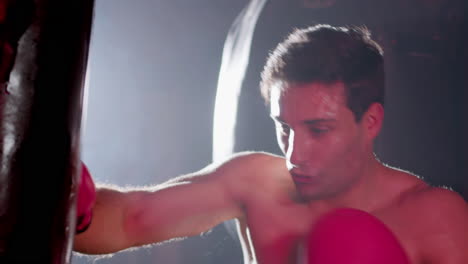 Strong-male-boxer-hitting-punching-bag-while-working-out