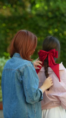 mother styling daughter's hair in the park