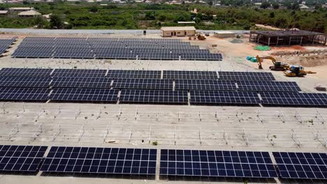 Aerial-forward-descending-dolly-view-over-dusty-PV-arrays-and-ground-at-Jambur-solar-PV-power-plant