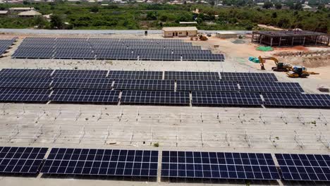 vista aérea de dolly descendente hacia adelante sobre matrices fotovoltaicas polvorientas y tierra en la planta de energía fotovoltaica solar de jambur