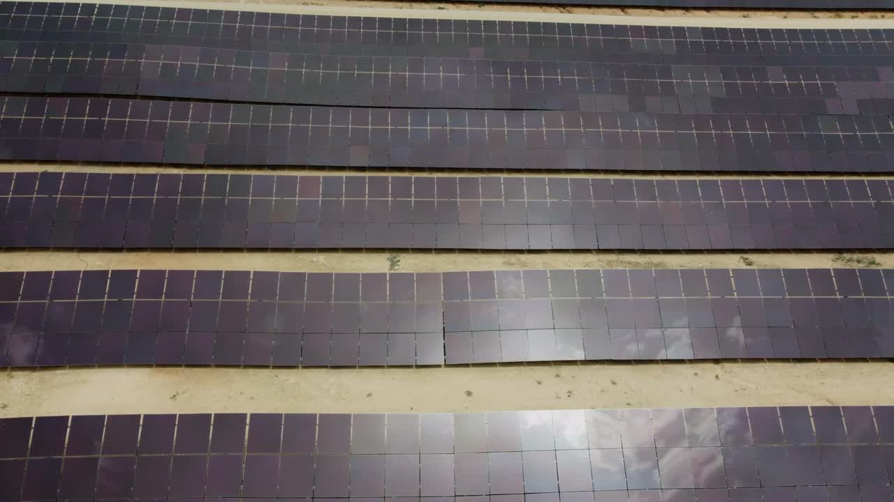 Drone slowly pans out over solar panels in a solar power station also called solar park