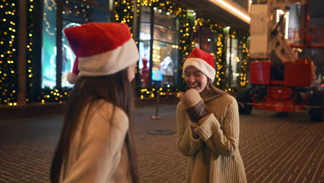 two friends in christmas hats laughing at night