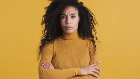 una mujer afroamericana enojada sobre un fondo naranja.