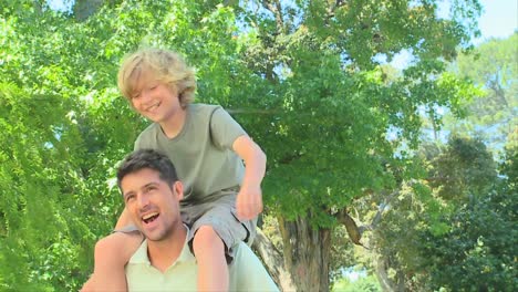 Young-boy-smiling-on-his-fathers-shoulders