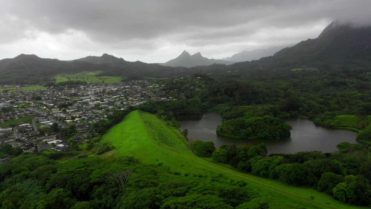 Malowniczy staw Loko Waimaluhia z małą wyspą w ogrodzie botanicznym Hoomaluhia na nizinach Kaneohe, na Nawietrznej Stronie Oahu, ujęcie lotnicze typu dolly.
