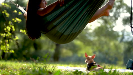 joven modelo de raza mixta hamaca de roca en el parque natural del bosque con su pequeño perro cura