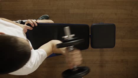 caucasian man lifting arm dumbbell in right arm - top shot