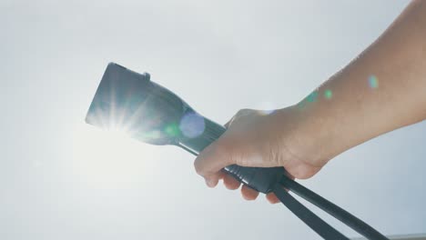 Closeup-hand-grasping-an-EV-plug-for-electric-vehicle-as-progressive-idea.