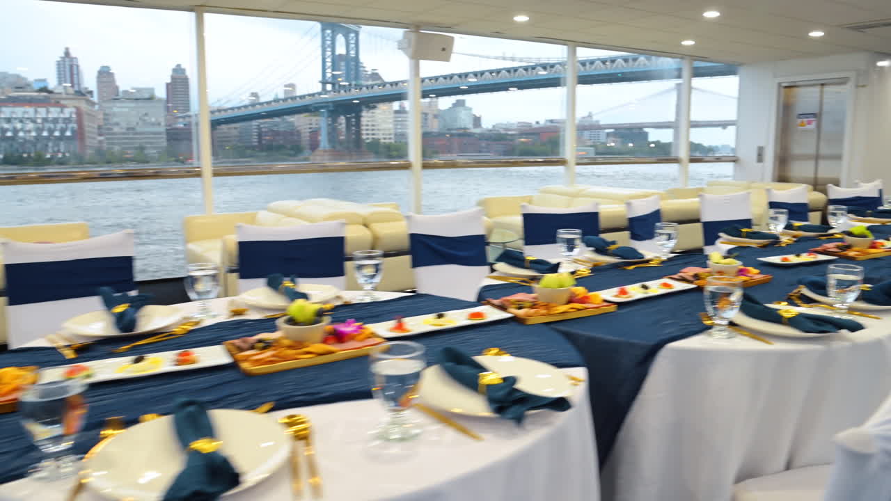 Preparación de un banquete en un yate con vistas al skyline de Nueva York. Preparación elegante de una mesa de banquete en un yate con el puente de Manhattan y el skyline de Nueva York al fondo