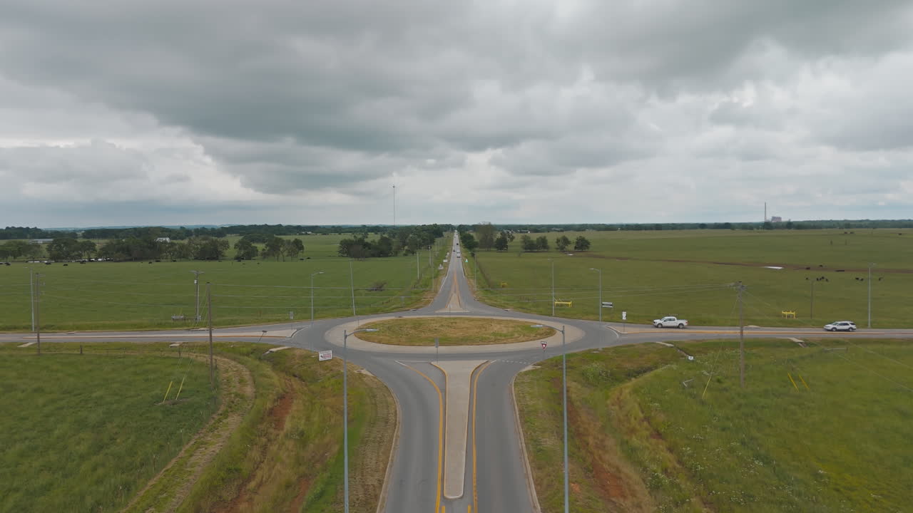 Straight farm roads and roundabout running through green fields in Cherokee City, Arkansas, aerial descend tilt up