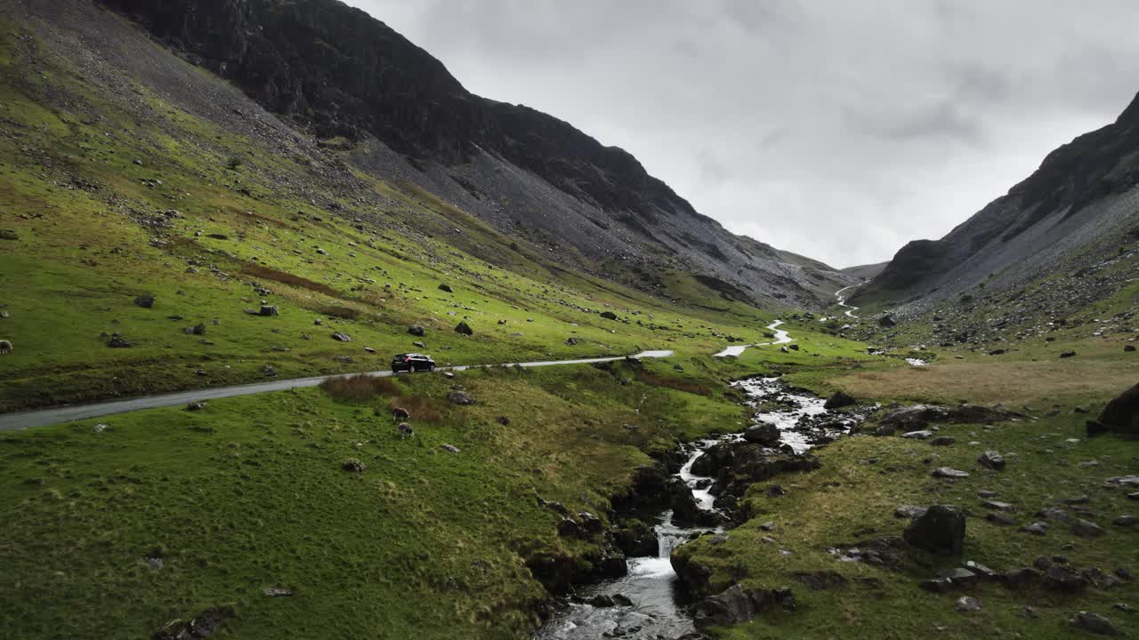 Un'auto che sale l'Honister Pass verso una miniera di ardesia nel Lake District inglese in una giornata cupa e nuvolosa
