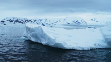 iceberg flotando en el océano en el mar con las montañas de la antártida en la costa de la península antártica, hermoso dramático paisaje costero azul y paisaje marítimo en invierno helado escena del mar con hielo