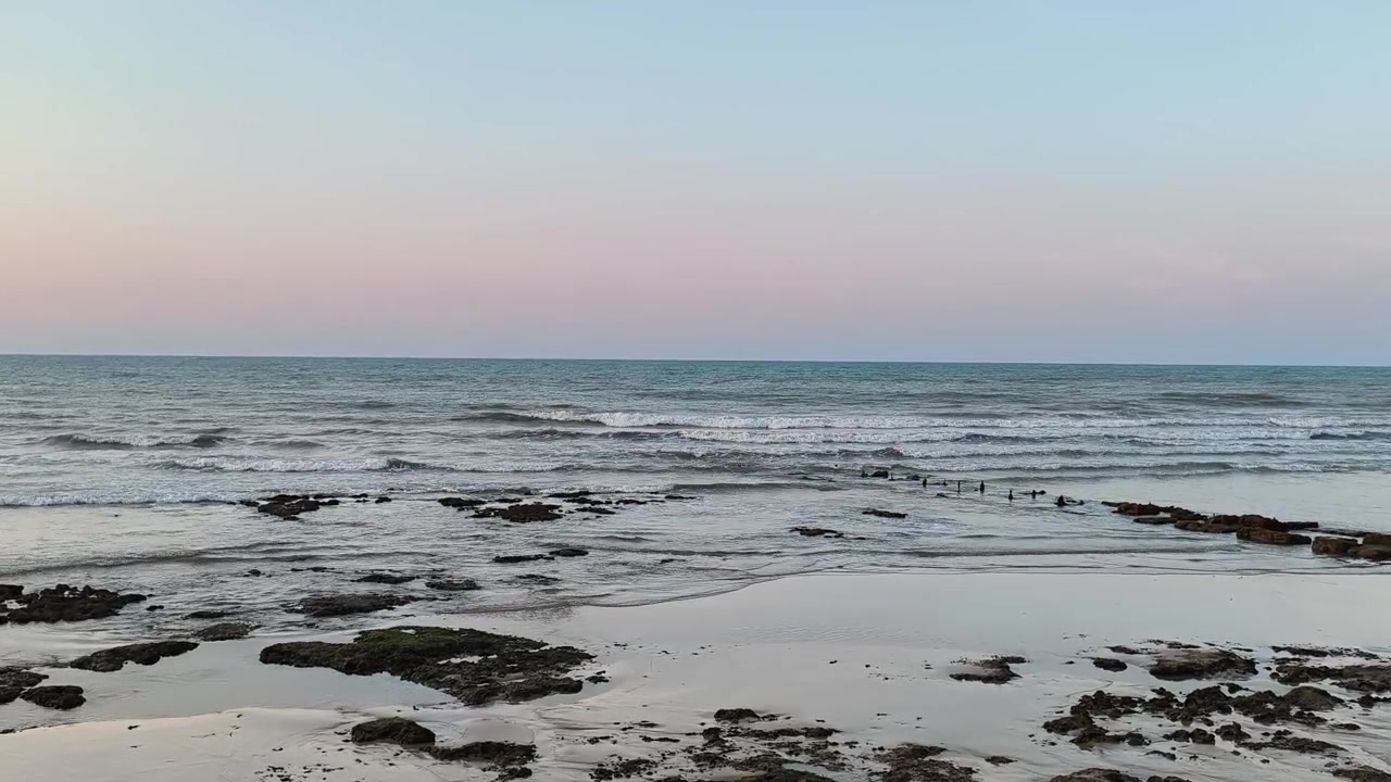 Onde leggere che si infrangono su una spiaggia rocciosa al tramonto