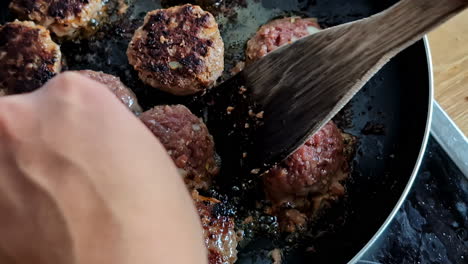 searing meatballs in a frying pan on the stove - isolated close up