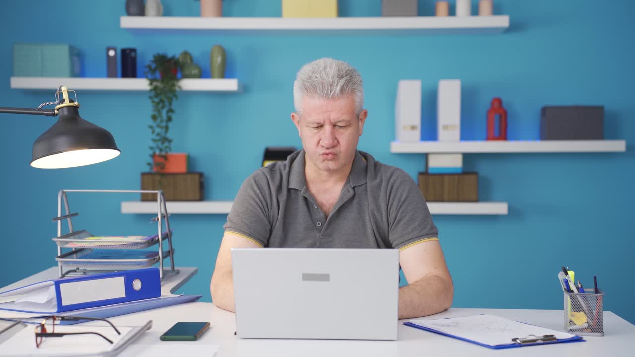 홈 오피스 직원 남자가 노트북에서 긴장해서 기다리고 있습니다.