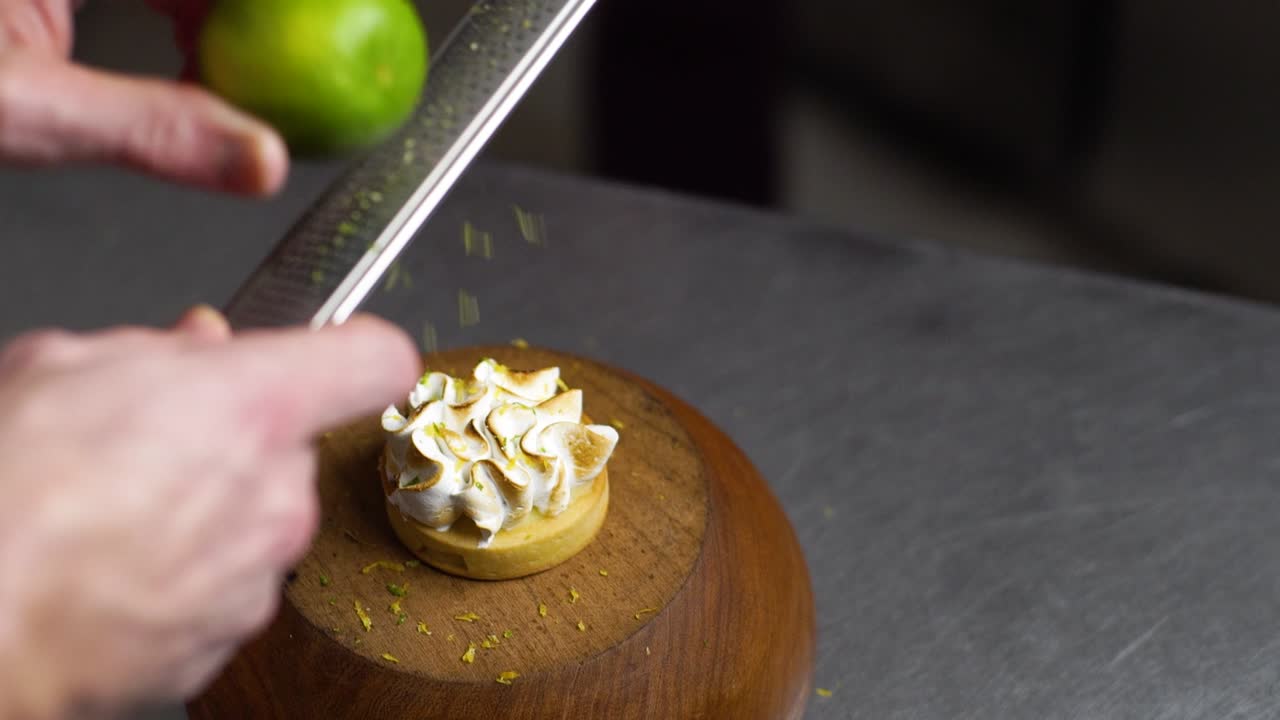Grating lemon zest on a small lemon cake decorated with fluffy mousse