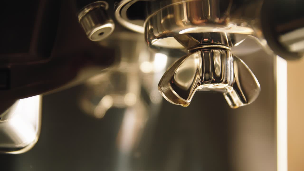 포타필터 출구에서 천천히 흘러내리는 뜨거운 커피의 느린 클로즈업