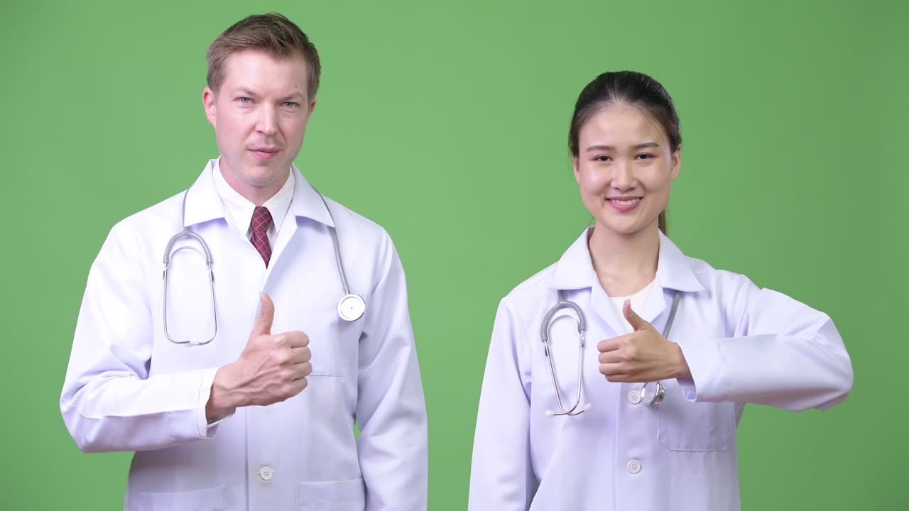 Multi-ethnic couple doctors giving thumbs up together