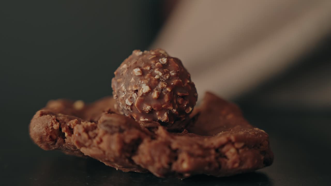 Hand placing chocolate candy on cookie dough indoors daytime