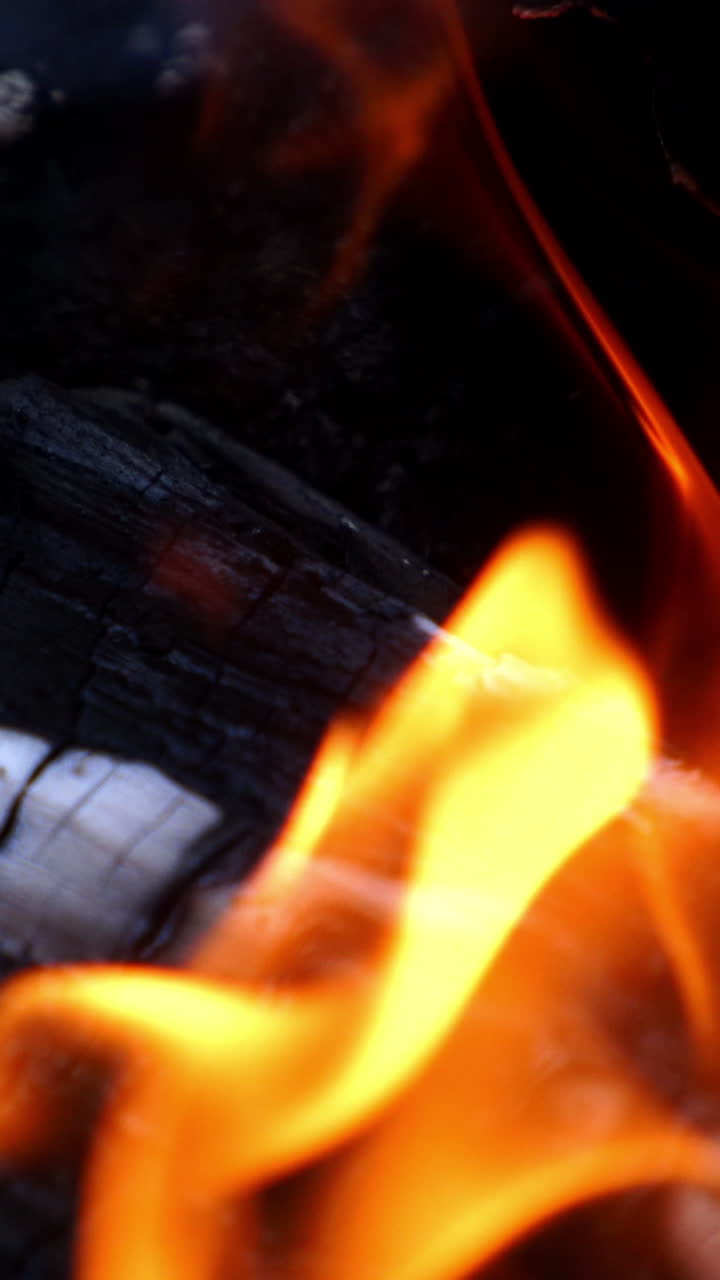 Bonfire. Burning logs in orange flames. Beautiful fire burns brightly. Embers of the fire climb up. Vertical video