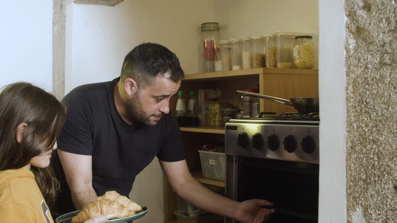 padre solícito enseñando a su hija cómo usar el horno.