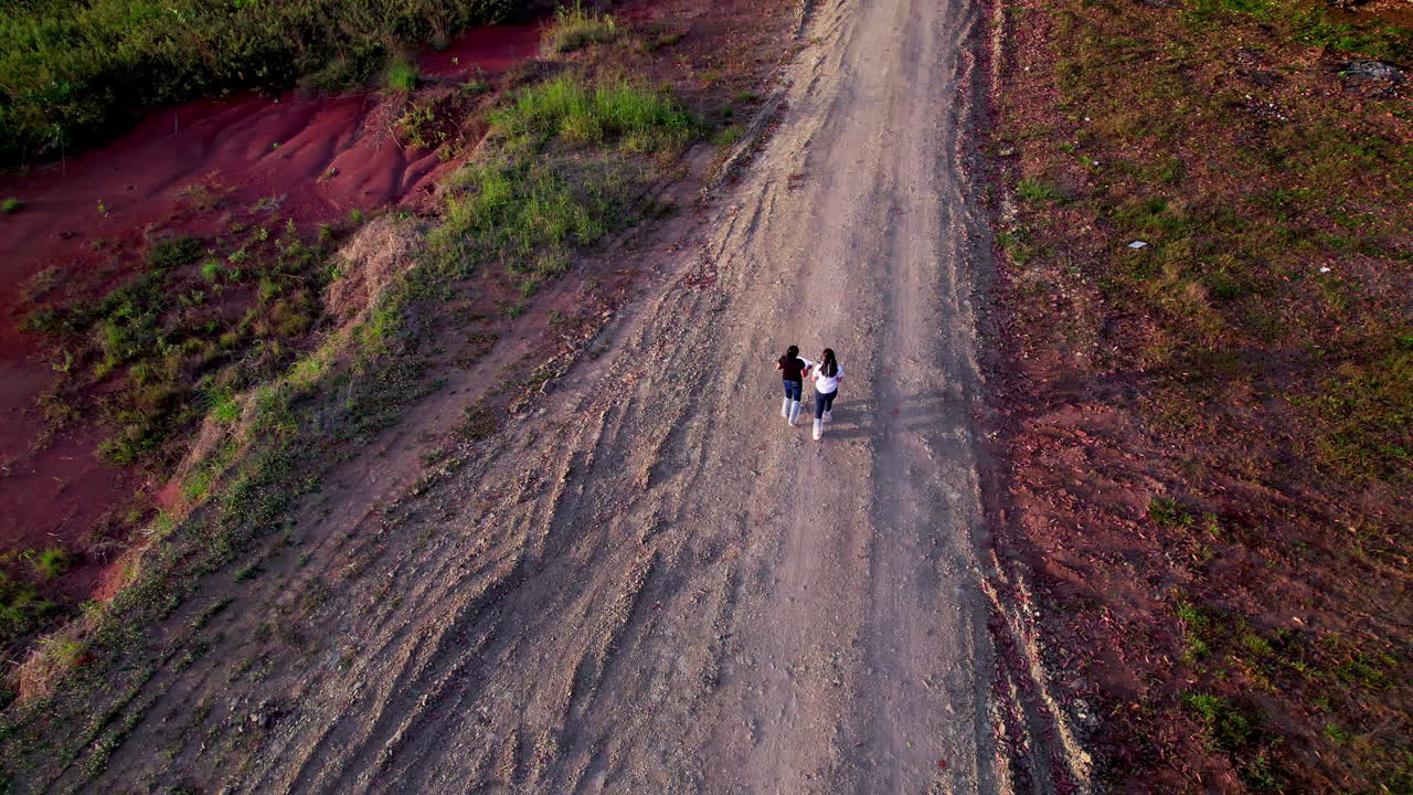 toma aérea de un par de amigos caminando por un camino de tierra en san martín