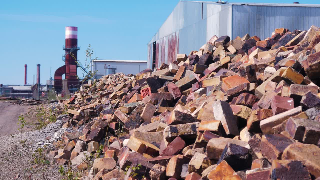버려진 소련 중금속 녹는 공장 리파자스 메탈루그 영토, 파편 더미, 오래된 벽돌 더미, 먼 굴뚝과 창고, 화창한 날, 중간 샷의 외부 전망