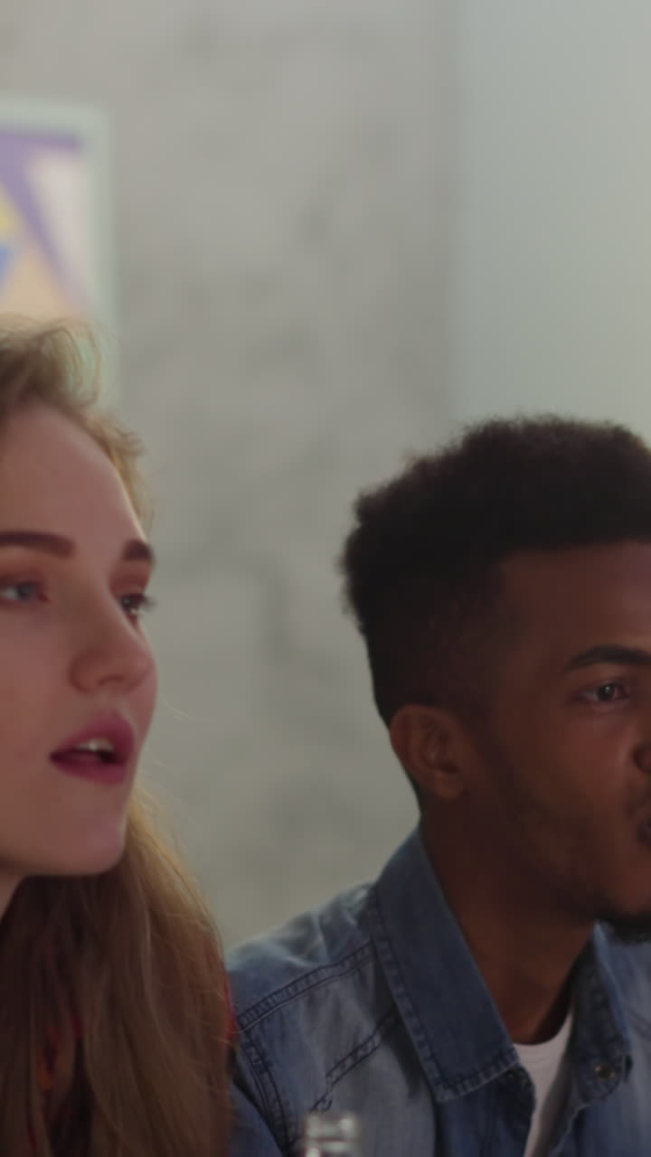 locos jóvenes fanáticos del béisbol saltan del sofá felices del gol final en el apartamento a cámara lenta. hombre con computadora portátil asintiendo con la cabeza. increíble juego de equipo en la competencia