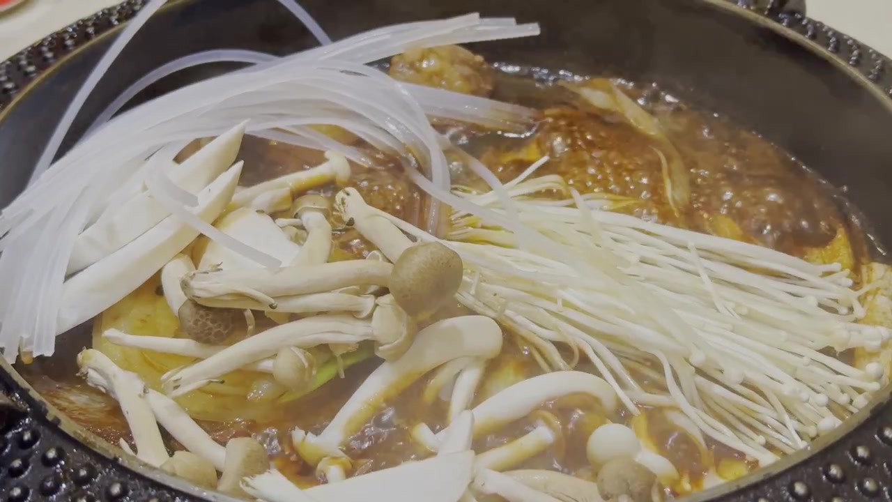 Video ravvicinato di brodo nero di sukiyaki giapponese che bolle vigorosamente in un hot pot. Zuppa fumante che sobbolle in una pentola tradizionale, mostrando l'autentica cucina giapponese hot pot e un'atmosfera calda e accogliente.
