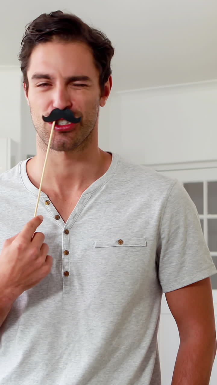 가짜 수염 을 가진 잘생긴 남자 가 얼굴 을 짓고 있다