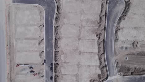 a drone looks straight down over a handful of meticulously flattened lots, poised and ready for the initiation of new home construction